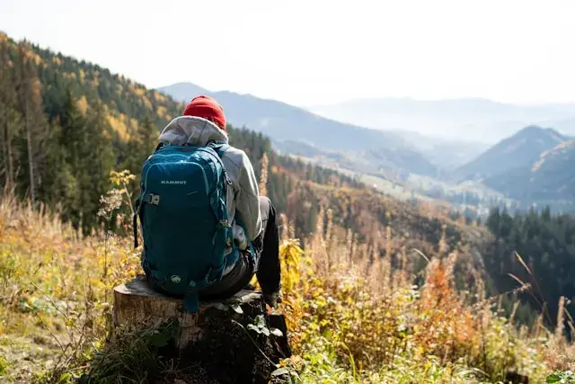 Solo hiker standing atop a misty mountain peak at sunrise, overlooking vast valleys—symbolizing the transformative power of outdoor adventure travel.