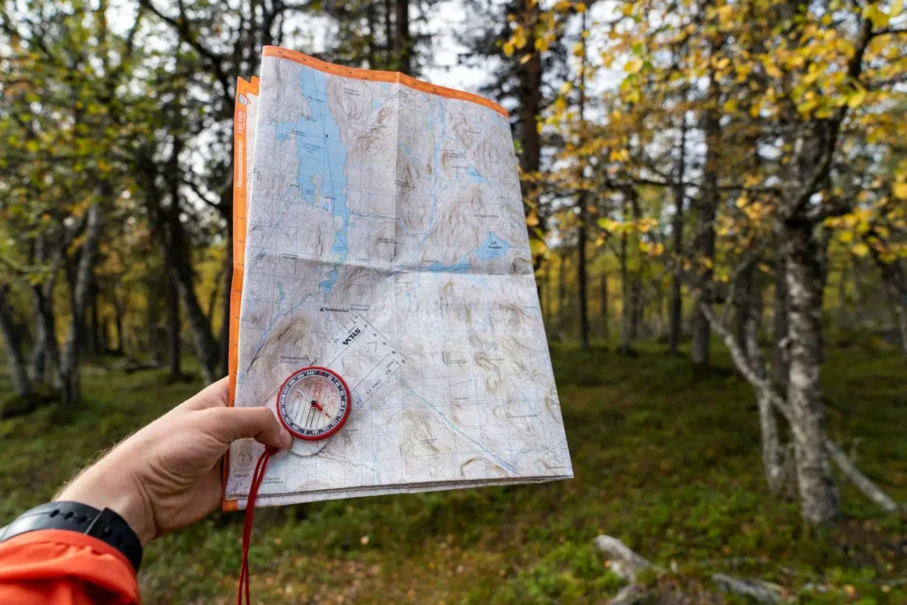 Traveler using a map and compass to navigate through outdoor wilderness
