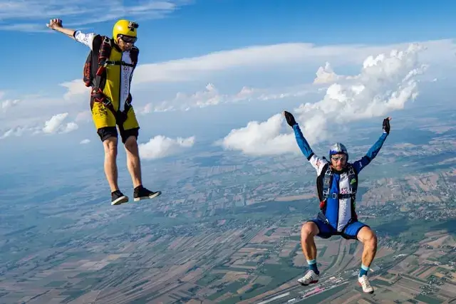A base jumper leaping from a cliff in Norway, soaring above a vast fjord under a clear blue sky.